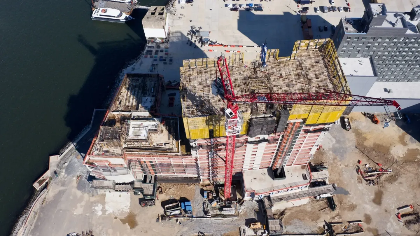 Aerial view of a large building under construction with cranes and scaffolding.