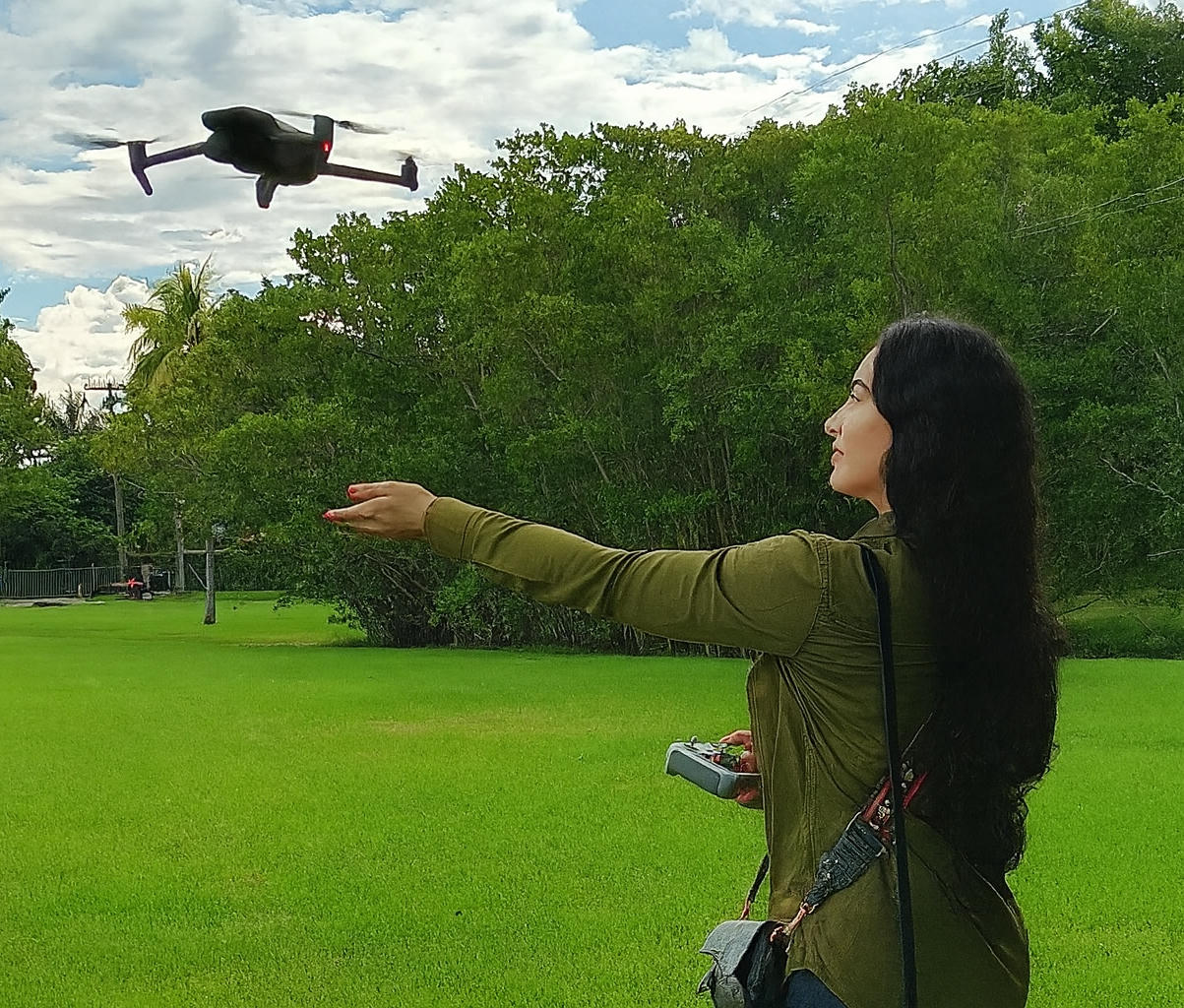 Woman controlling a drone in a green park.
