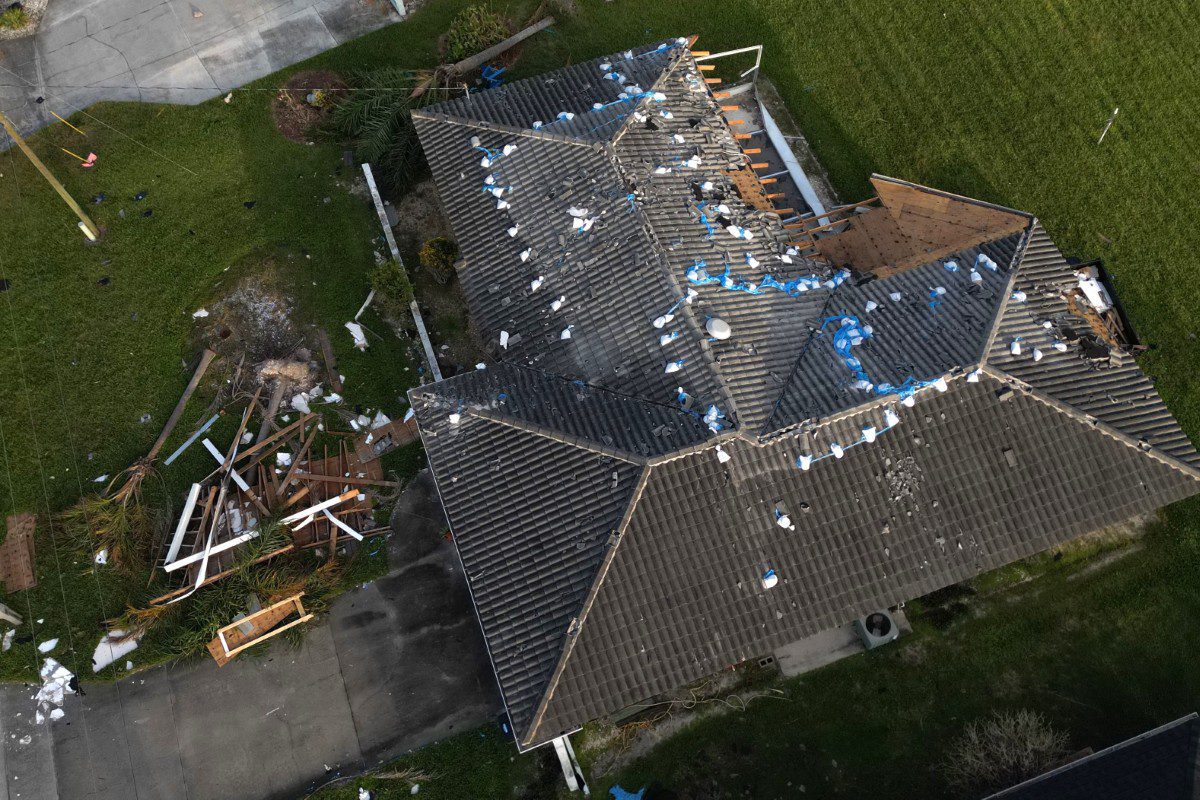 Damaged roof with scattered debris, aerial view.