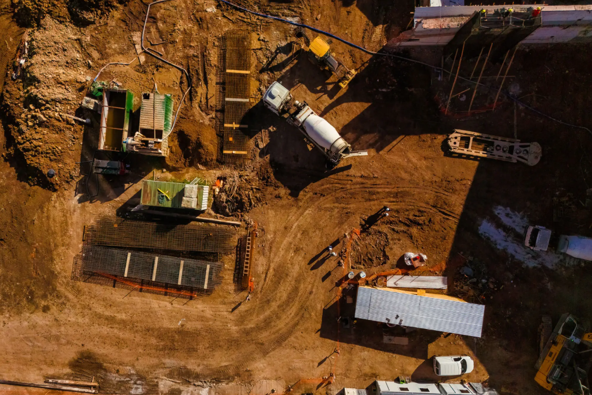 Aerial view of a construction site with machinery and workers on muddy ground.
